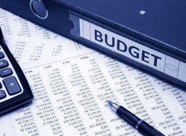 A budget report with a calculator, pen and binder with the words budget