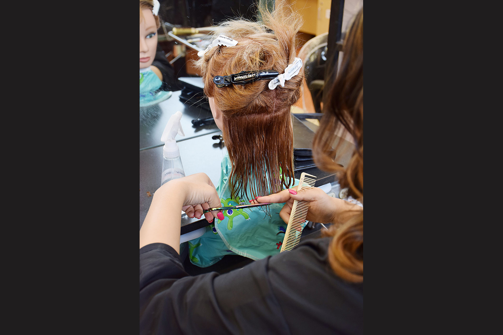 A student styles the hair of a female mannequin