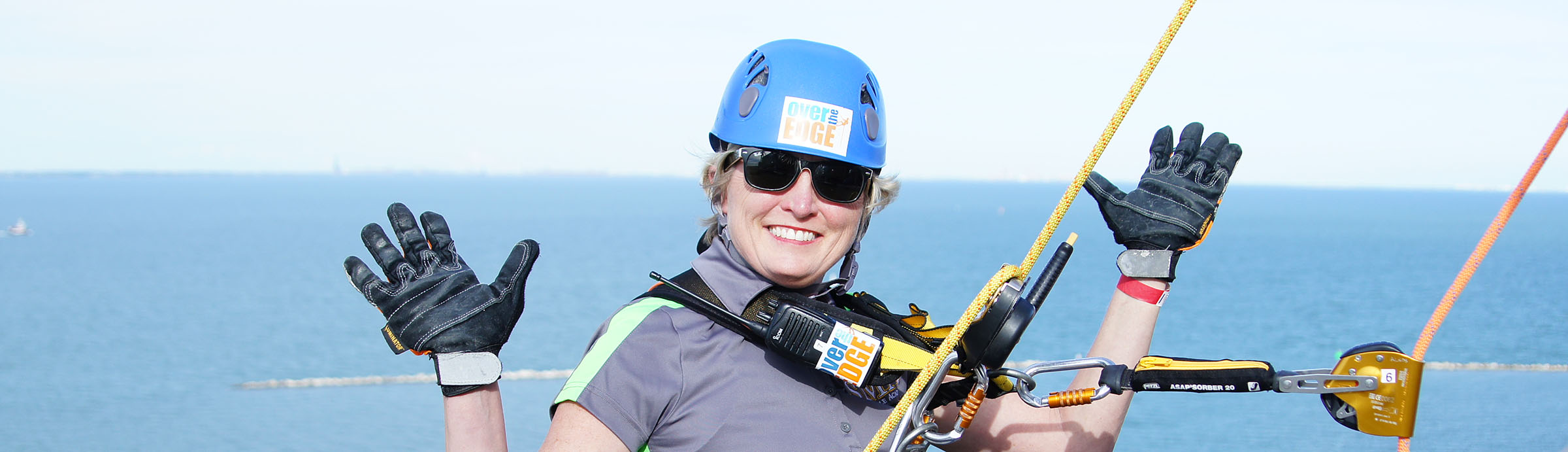 An Over the Edge participant is suspended from the top of a hotel overlooking the bay