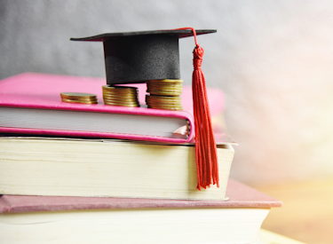 A stack of books with coins and a graduation cap