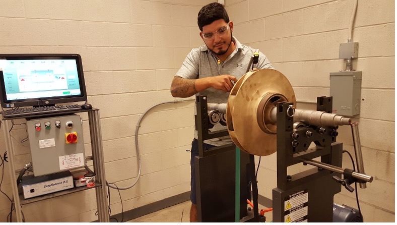 Man operating a piece of rotating machinery with safety goggles on.