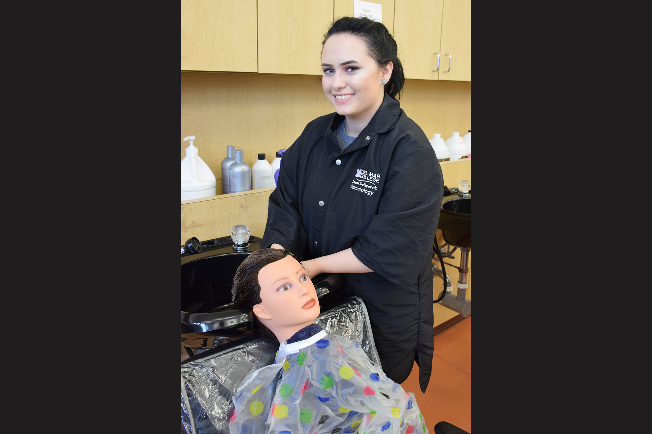 A student washes the hair of a female mannequin