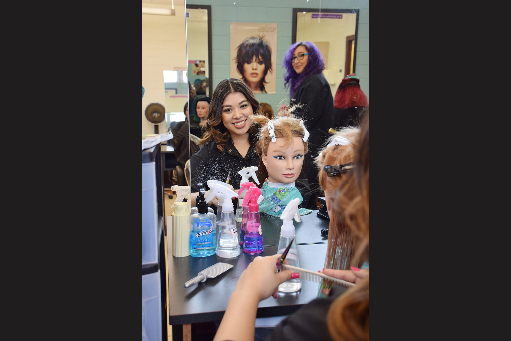 A student styles the hair on a mannequin