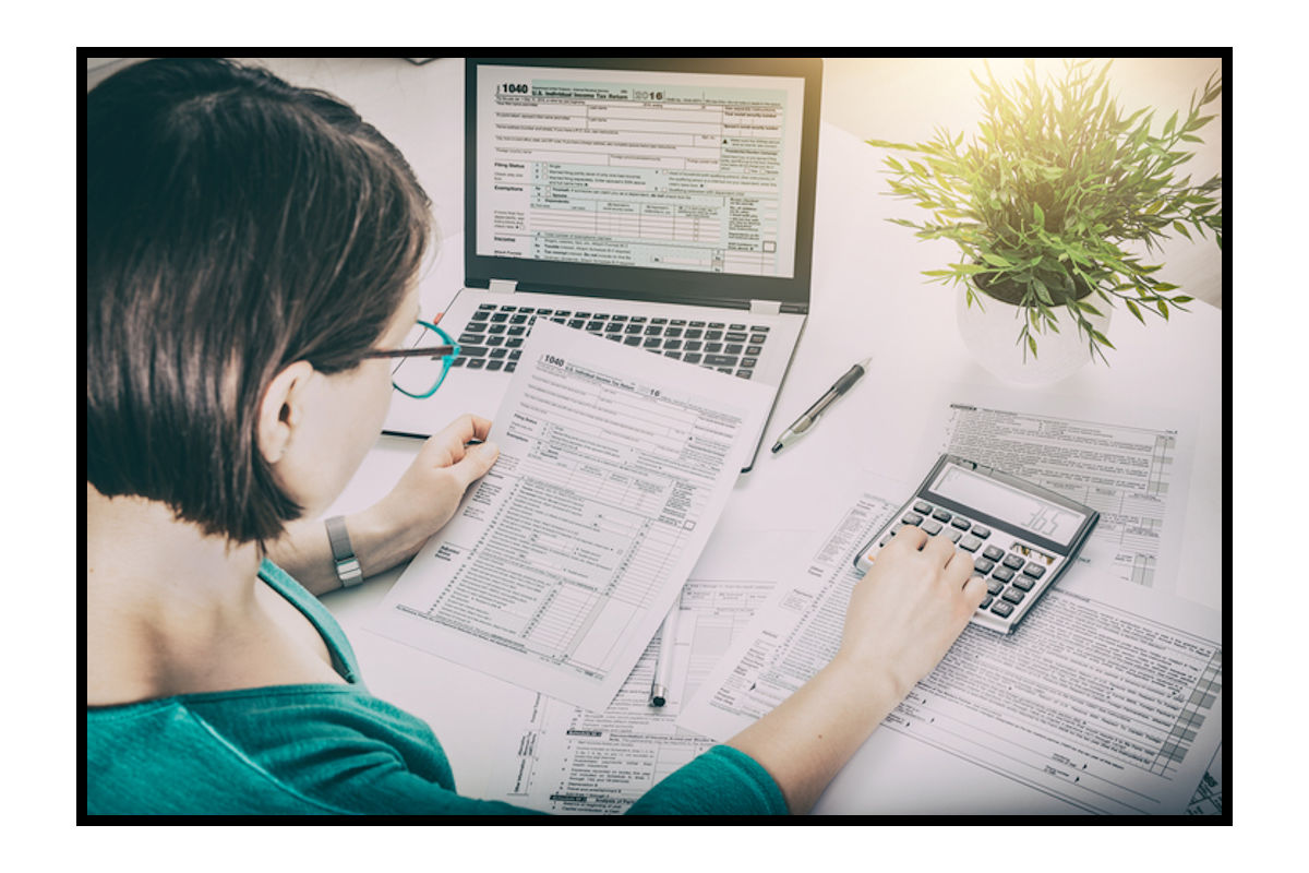 Woman works on tax documents using a computer and calculator