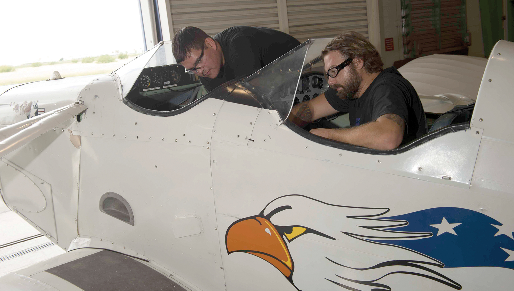 Two aviation maintenance technicians working on an airplane.