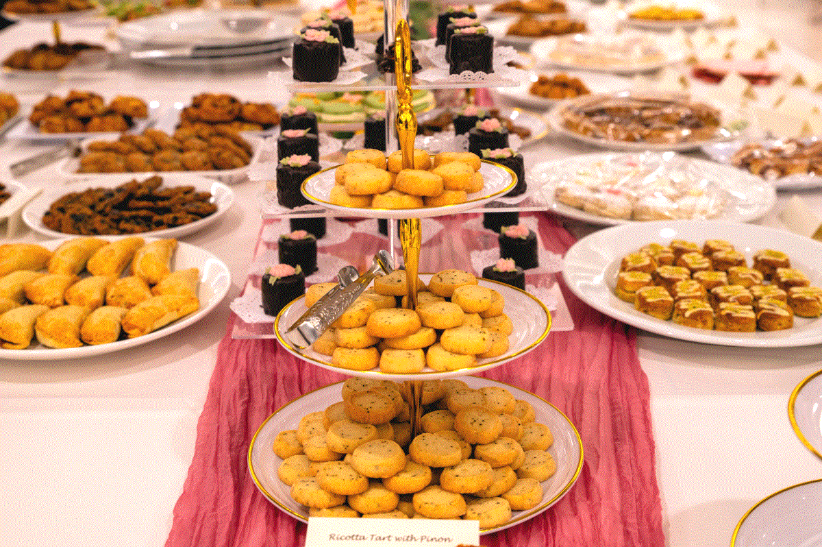 An assortment of desserts on a tiered stand and surrounding platters on a buffet table at the Annual Tea Party.