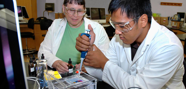 A biology student working with another in a science lab.