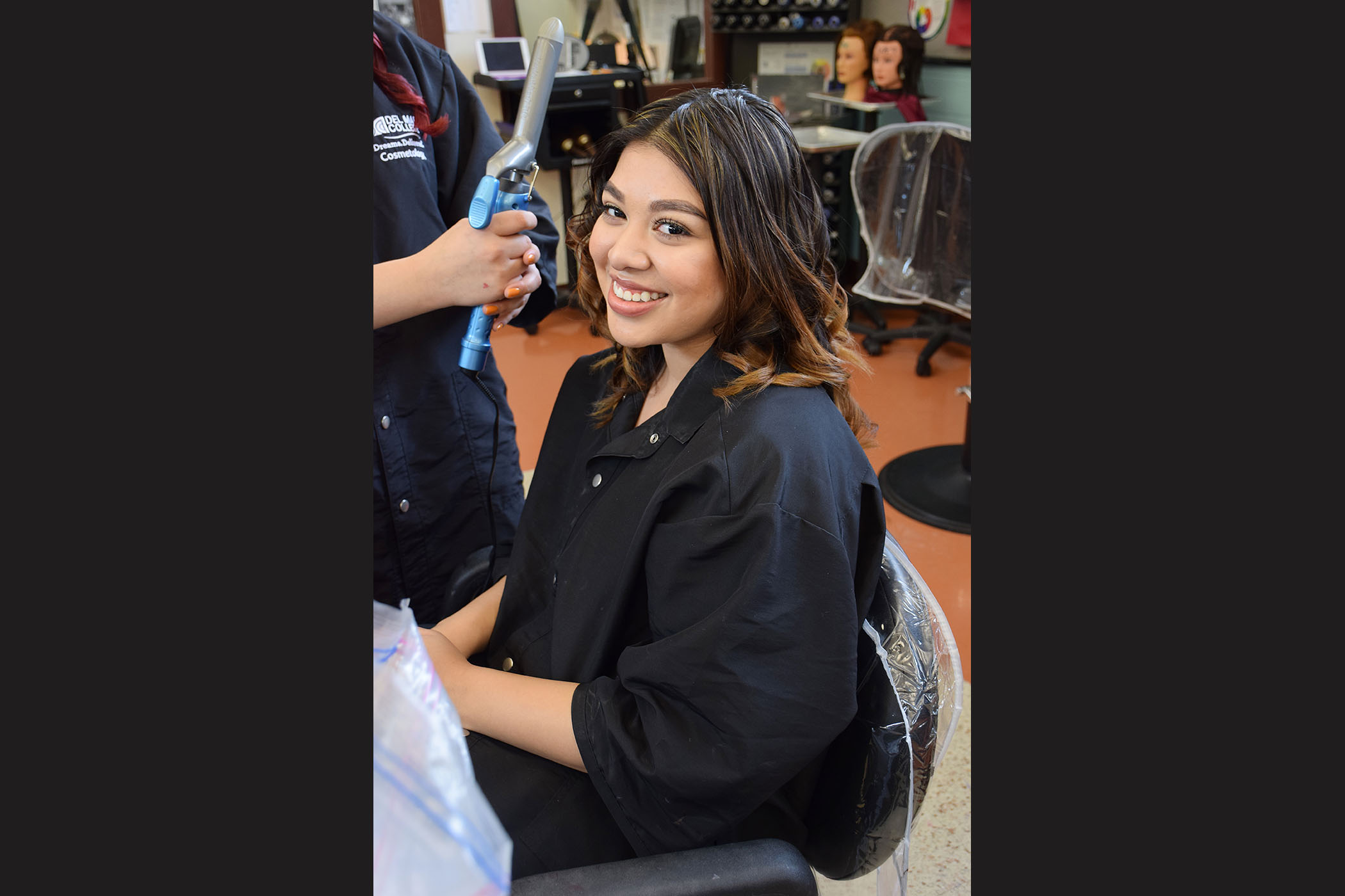 A student sits in a salon chair