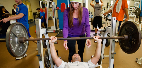 An instructor spots a student who is benchpressing.