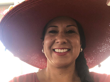 Teresa Saldivar, smiling, in a colorful hat