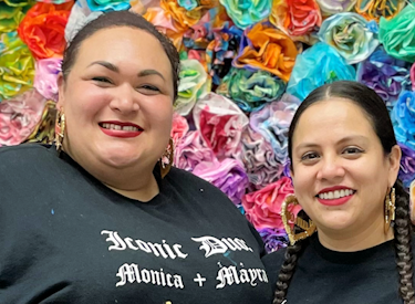 Monica Garcia and Mayra Zamora standing in front of a flower wall