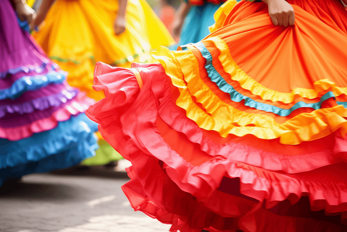 Colorful skirts in red, orange, yellow, and purple swirl together, showcasing ruffled hems in a dynamic dance setting.