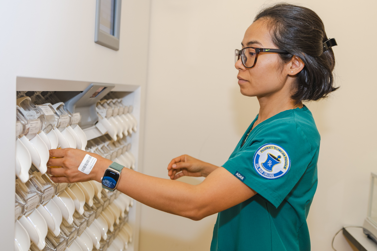 Pharmacy technician using pill dispenser.