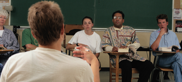 An instructor speaks to students in a classroom.