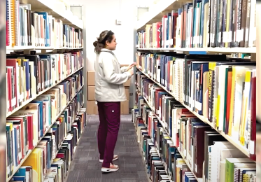Female student in the library looking at the books.