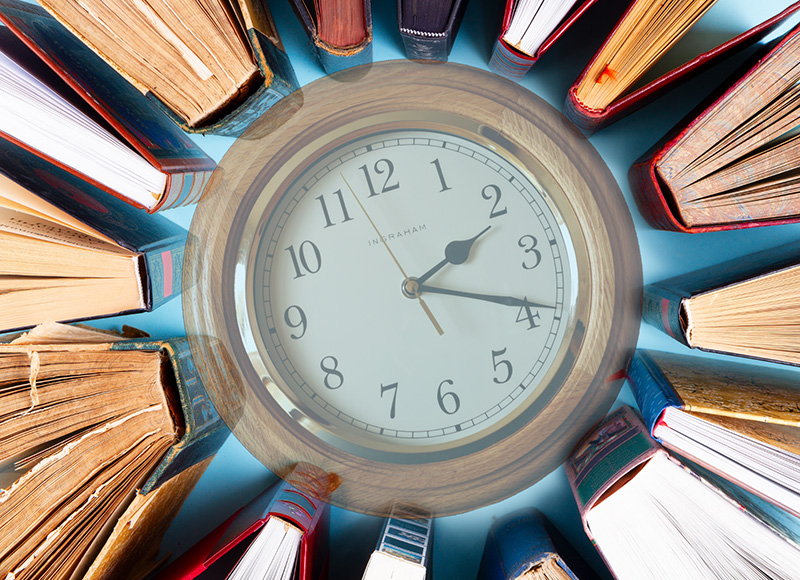 A clock sitting on a table surrounded by books