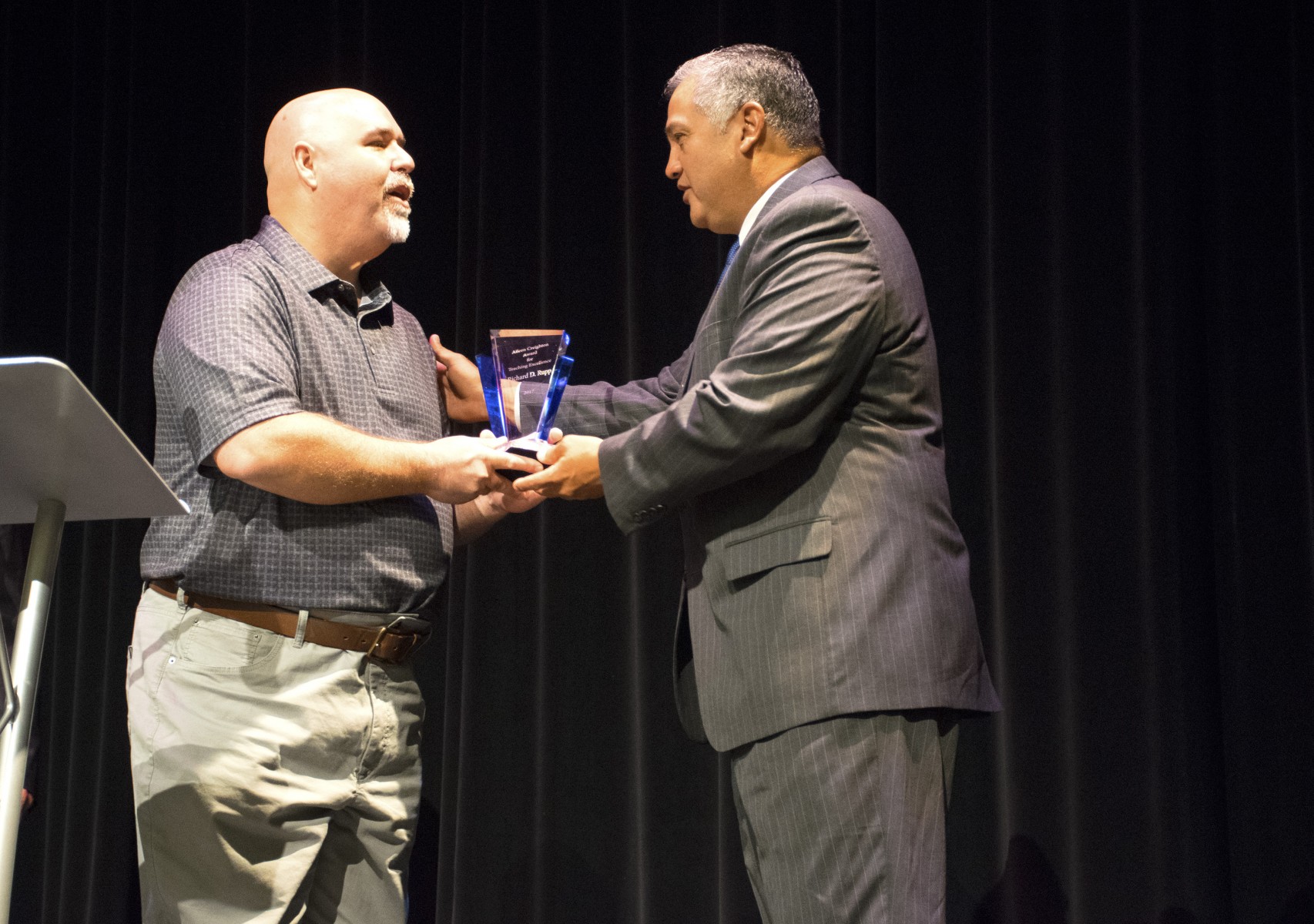 Richard Rupp accepts an award on stage from President Mark Escamilla.