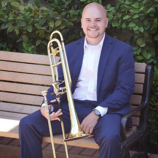 Jared Dalgleish sitting on a bench holding trombone