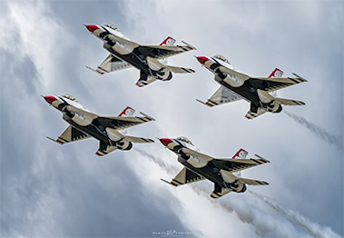 Four fighter jets in diamond formation against cloudy skies.