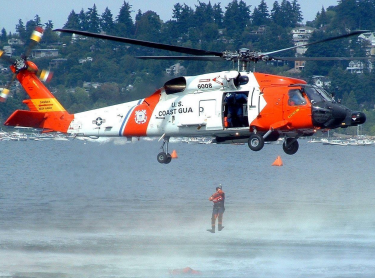 a Coast Guard helicopter lifting a soldier out of the water
