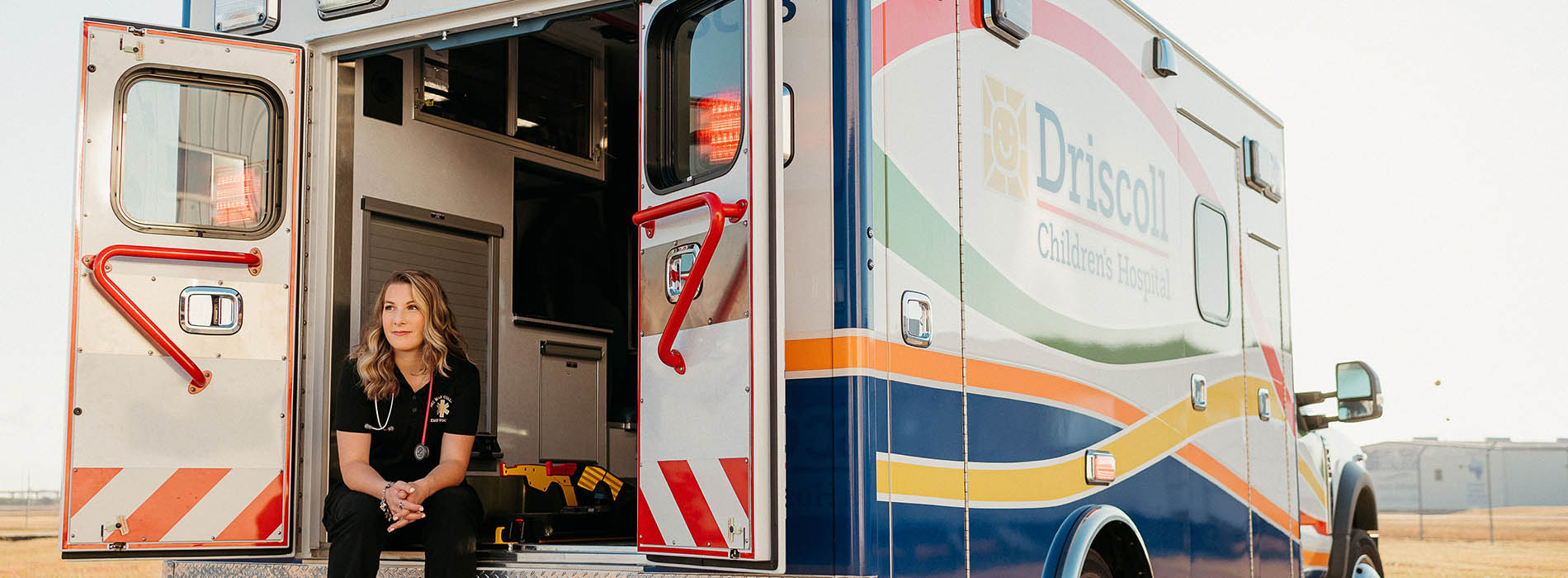 DMC graduate Mackenzie Scott sitting in the open rear door of an ambulance